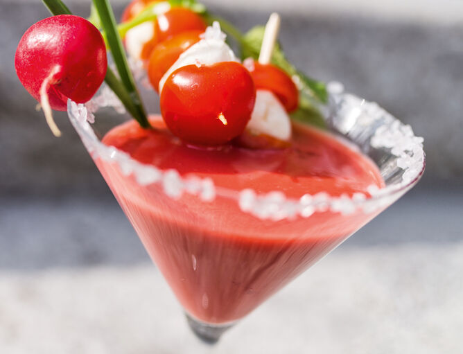 Bicchiere da Martini con cocktail rosso per l'happy hour con pomodoro e bastoncini di mozzarella con Bambini Mozzarella Mini di GOLDSTEIG