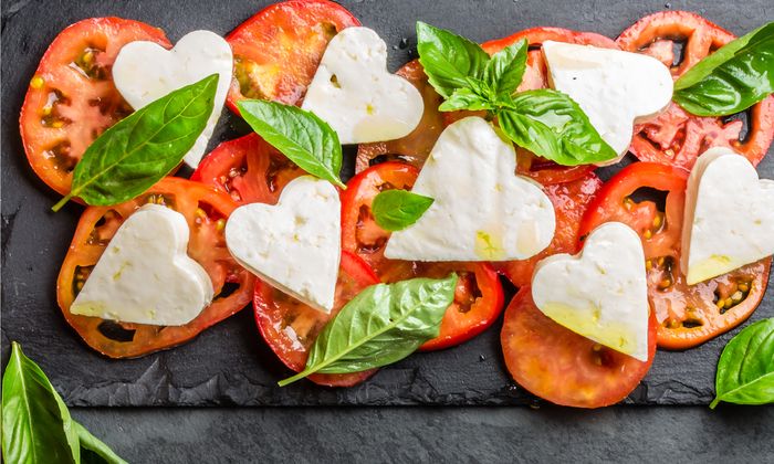 Pomodori, basilico e mozzarella di GOLDSTEIG a forma di cuore su un piatto di ardesia