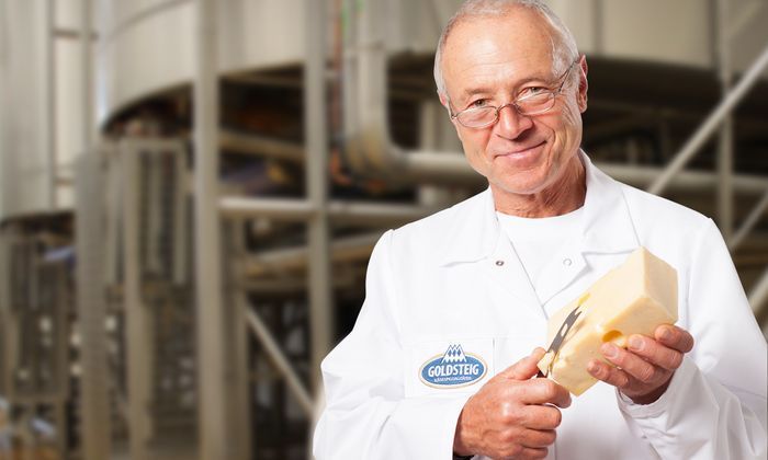 Le curiosità sulla mozzarella presentate dal maestro di formaggio GOLDSTEIG con un pezzo di Emmental nel caseificio Goldsteig