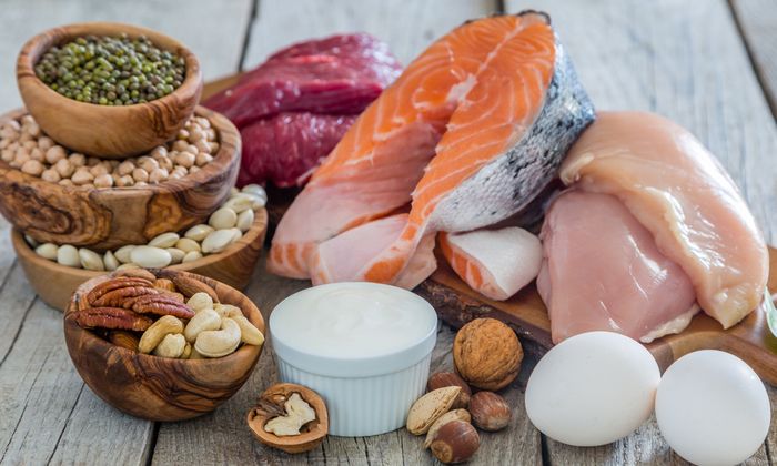 Cibi crudi come carne, pesce, noci, uova e yogurt su legno