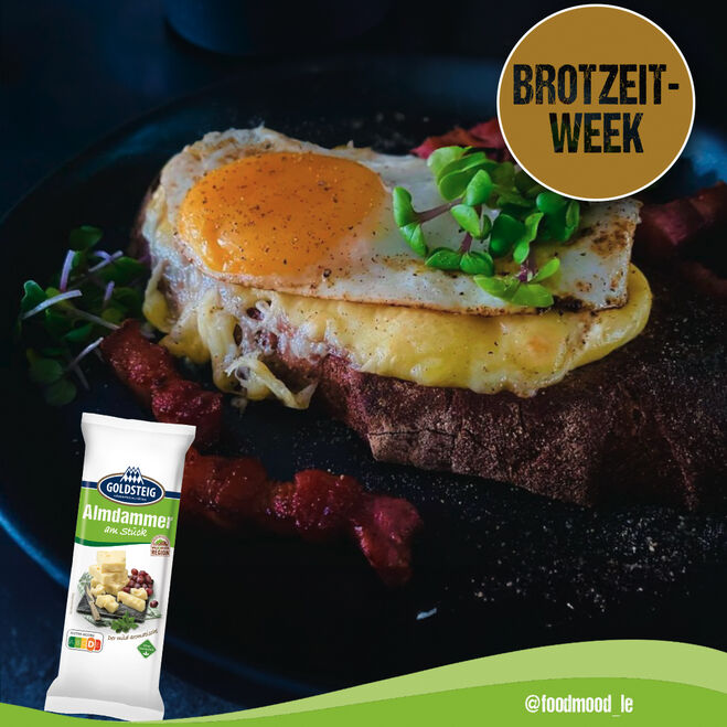 Promozioni e notizie (promotions-news) / post sui social media: Pane al formaggio grigliato con Almdammer in un unico pezzo di GOLDSTEIG su un piatto nero.