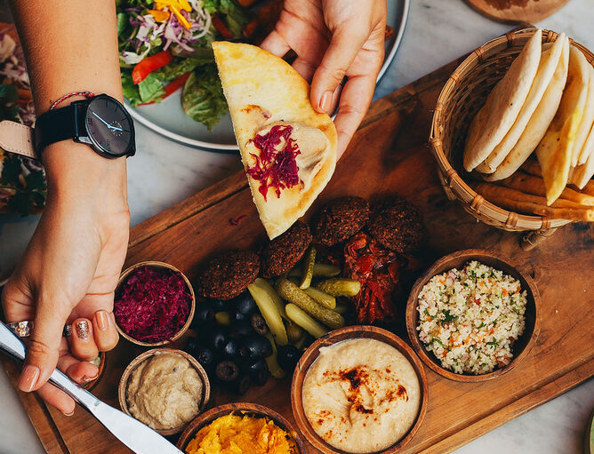Cucina di Levante con salsine di formaggio di GOLDSTEIG in ciotole di legno, pane bianco e cetriolini sottaceto su un piatto di legno