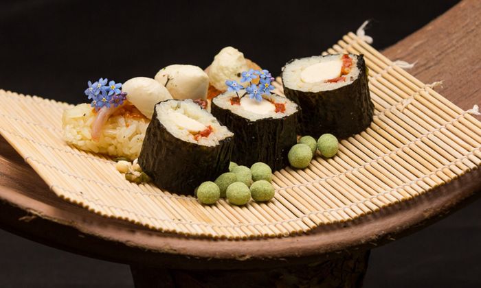 Ricetta sushi di mozzarella con Bambini Mozzarella Mini di GOLDSTEIG servita con noci e fiori di wasabi su un tappetino per sushi 