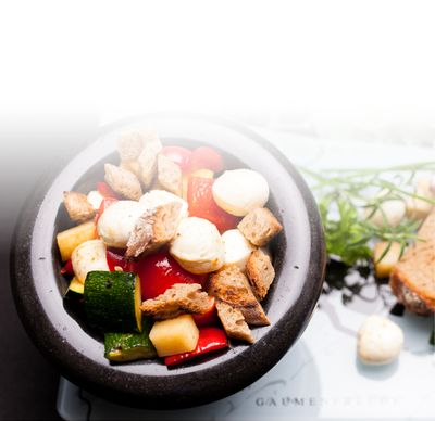 Ricetta della mozzarella Insalata di peperoni, carote e zucchine con Bambini Mozzarella Mini di GOLDSTEIG servita con erbe e pane in un vaso di pietra 