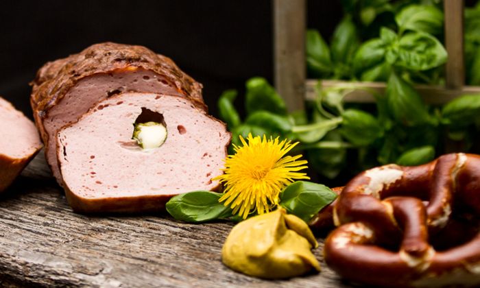 Ricetta della mozzarella Leberkäse ripiena di Bambini Mozzarella Mini di GOLDSTEIG con pretzel, senape, basilico e tarassaco su una tavola di legno 