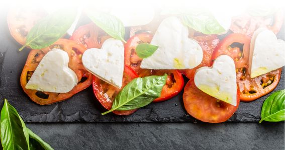 Fette di pomodoro condite con mozzarella a forma di cuore di GOLDSTEIG e basilico