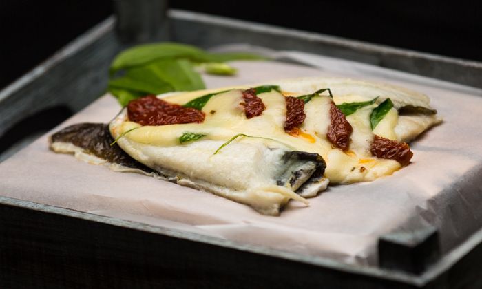 Ricetta della mozzarella Platessa con fette di mozzarella GOLDSTEIG, pomodori secchi e aglio selvatico su un piatto di ferro