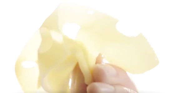 Una fetta di formaggio Emmental sottilissimo di GOLDSTEIG tenuta in una mano