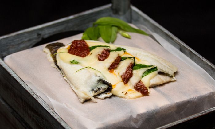 Ricetta della mozzarella Platessa con fette di mozzarella GOLDSTEIG, pomodori secchi e aglio selvatico su un piatto di ferro